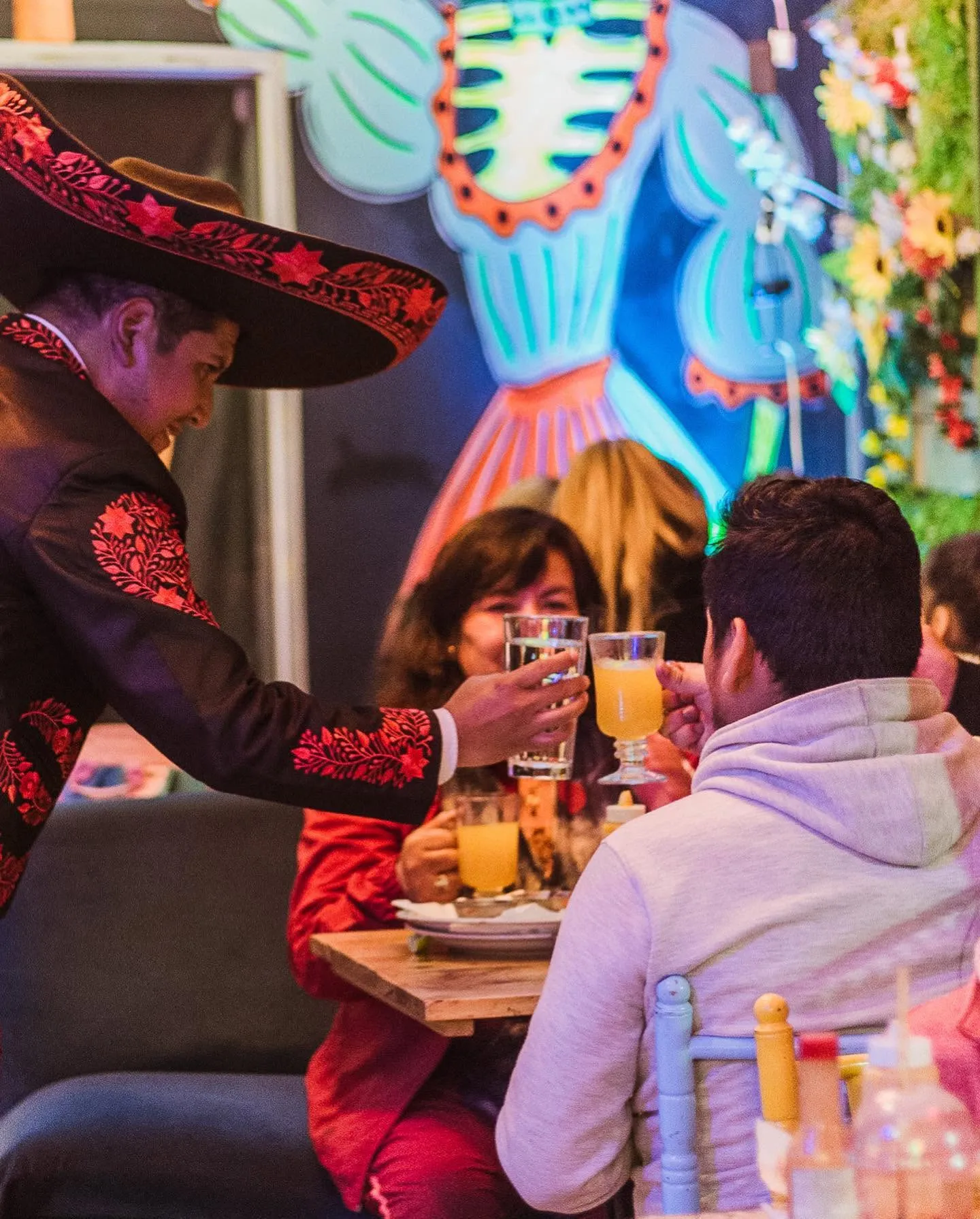 Mariachi brindando con una familia en su mesa
