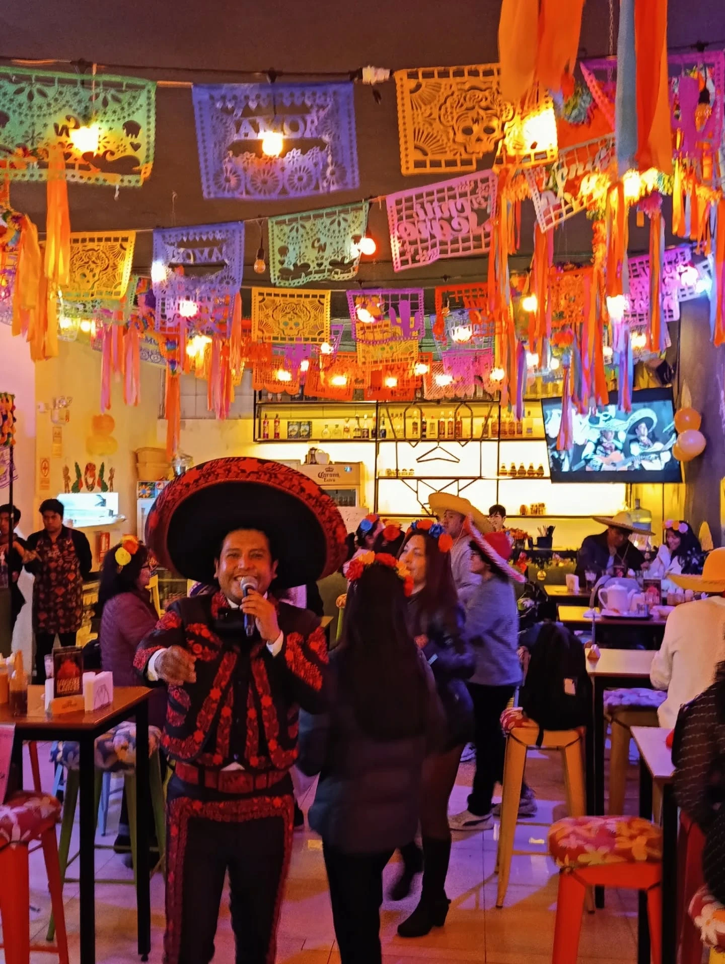 Mariachi cantando entre las mesas bajo el papel picado